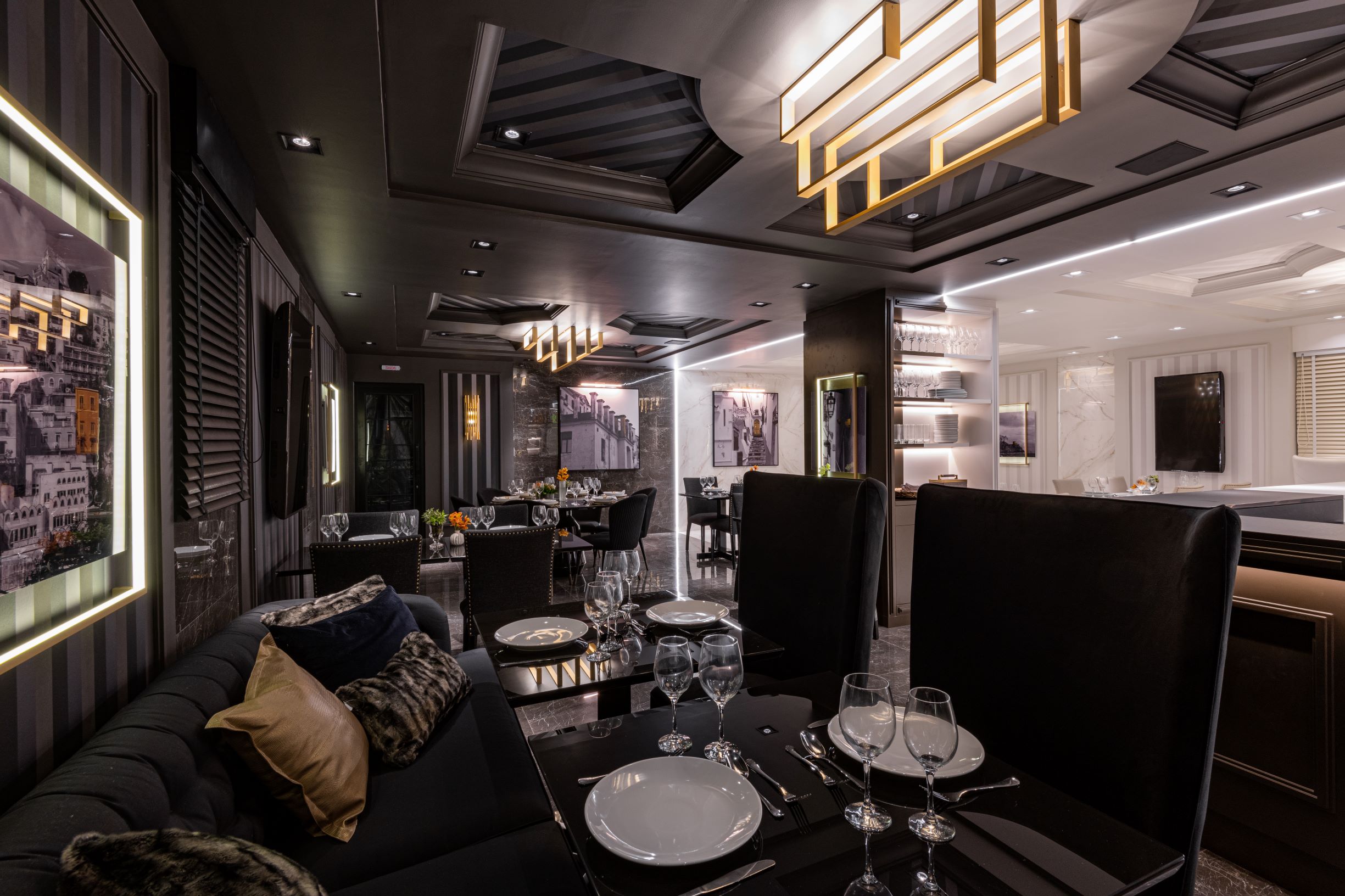 Restaurante Limone, CASACOR São Paulo 2019, Habitat Projetos Inteligentes. restaurante com conceito de dualidade. "lado noite", teto de gesso com relevo, cadeiras clássicas pretas, sofá preto clássico, mesa de mármore preto e utensílios. 