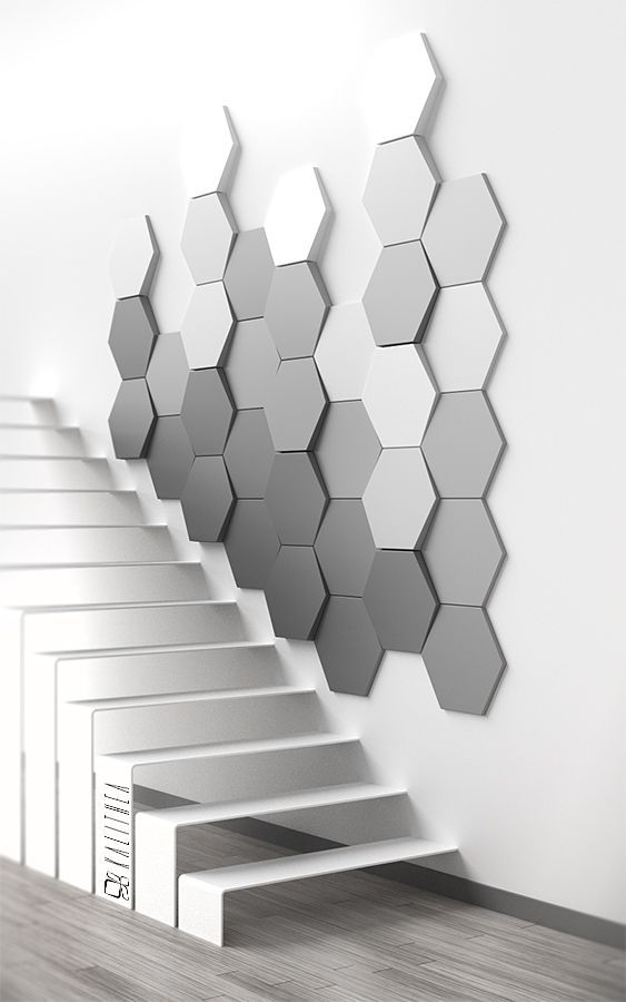 Parede com revestimento 3D. parede de acesso a escada está revestida com material 3D, tem formas hexagonais em degrade com tons de cinza.