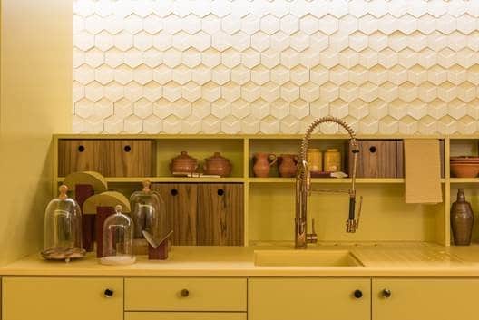 Cozinha amarela. gabinete, pia e prateleiras. parede com revestimento 3D discreto em formato hexagonal. 