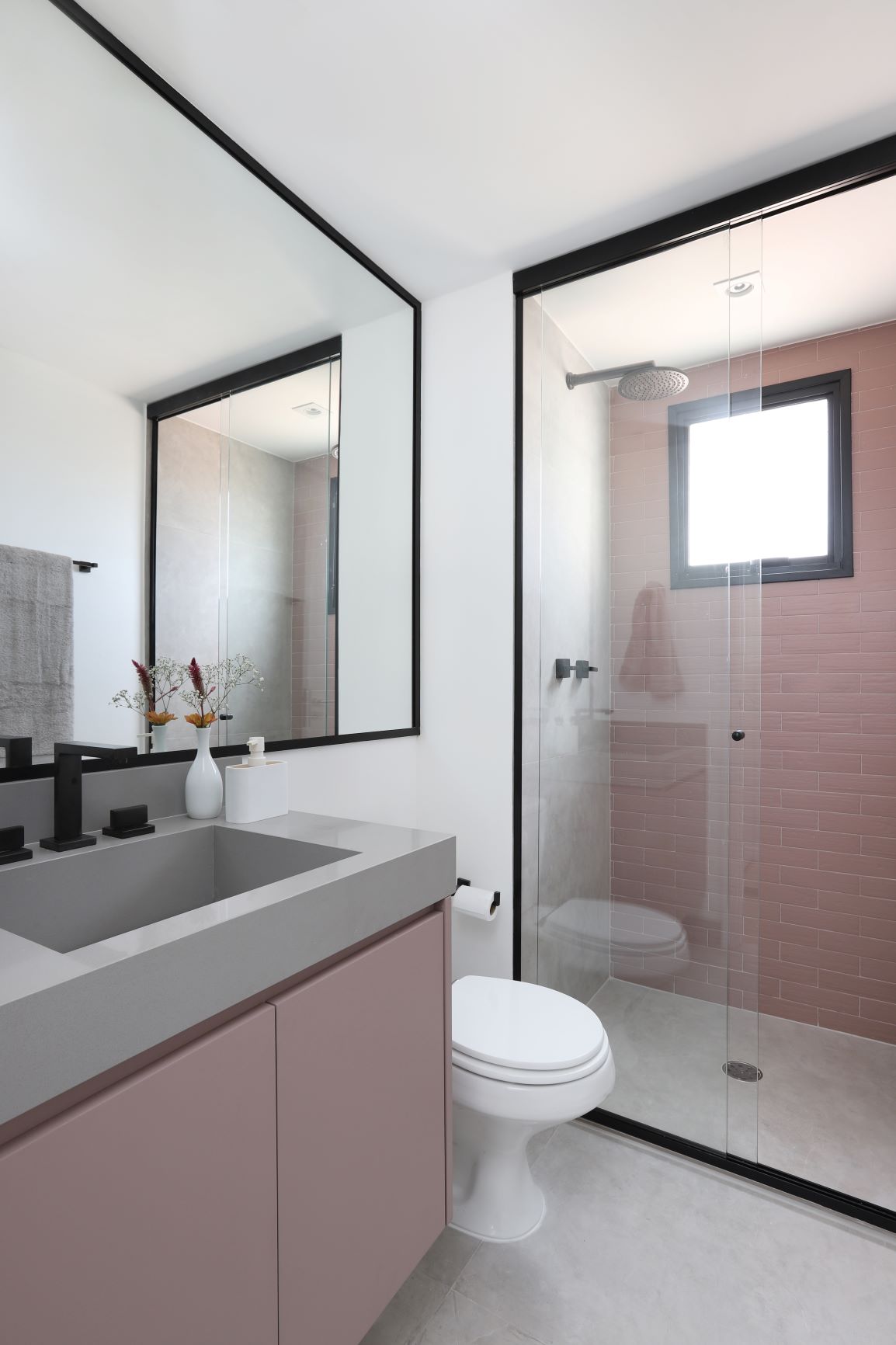 Banheiro com revestimento rosa e metais pretos. 