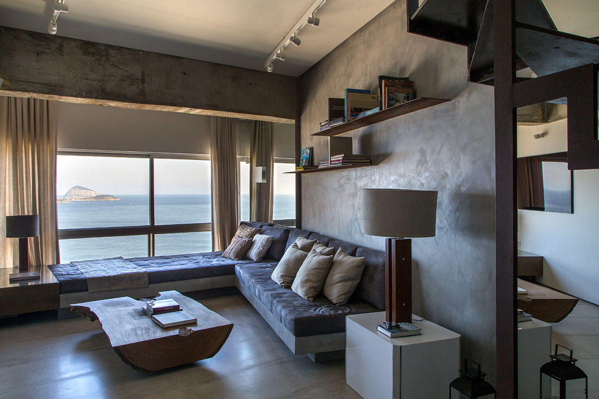 Estilo Minimalista Sala de estar. Parede com pintura minimalista, mesa de madeira natural e grandes janelas com visão para o mar.