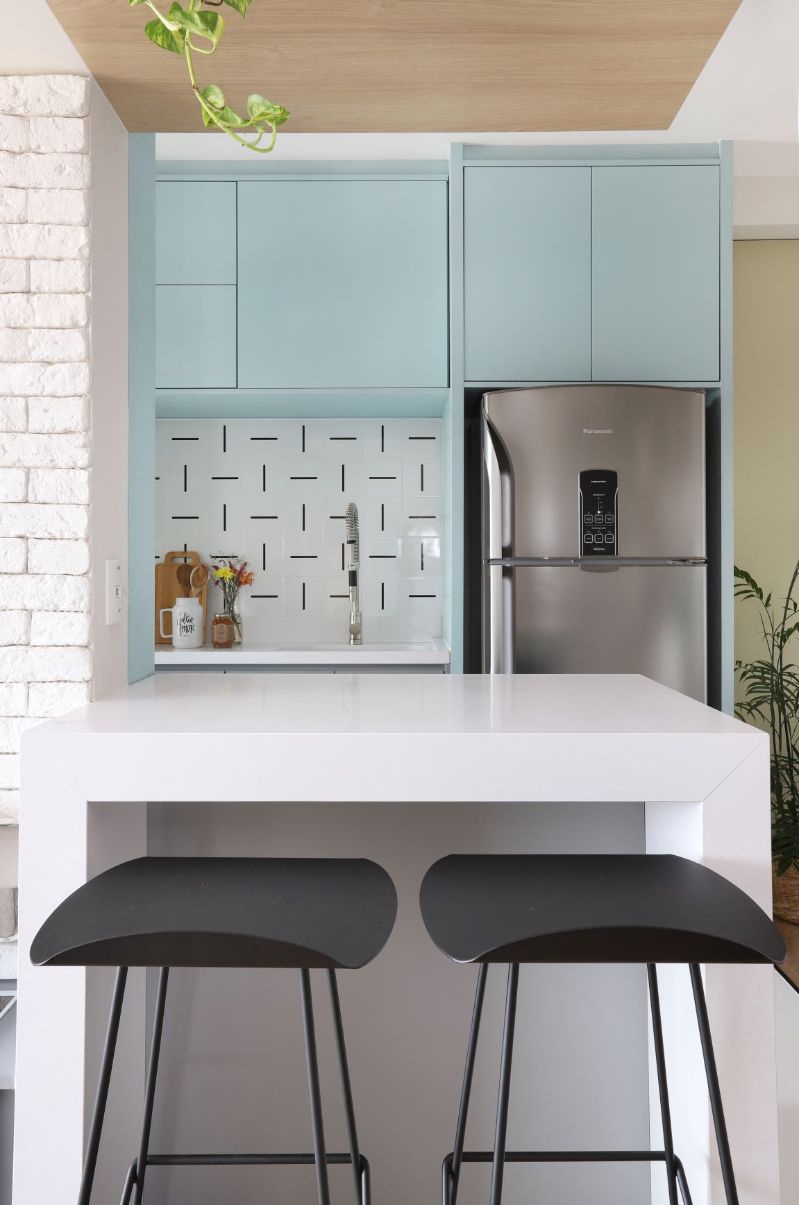 Apartamento com cores definidas a partir da escala Pantone. Cozinha com marcenaria em tom azul pastel e balcão branco. 