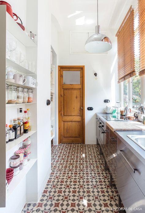 Cozinha com estilo rústico com ladrilhos clássicos, paredes brancas e prateleiras com utensílios e mantimentos.