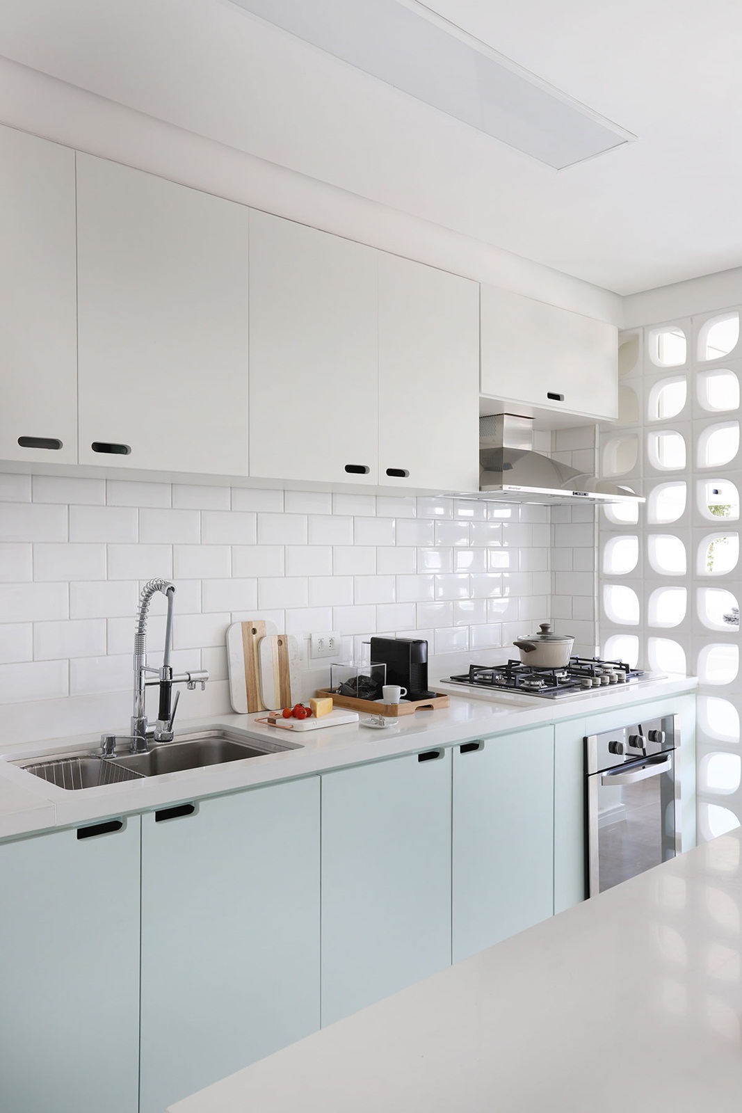 Cozinha pequena com azulejo branco metro, armário branco com verde claro e cobogó.