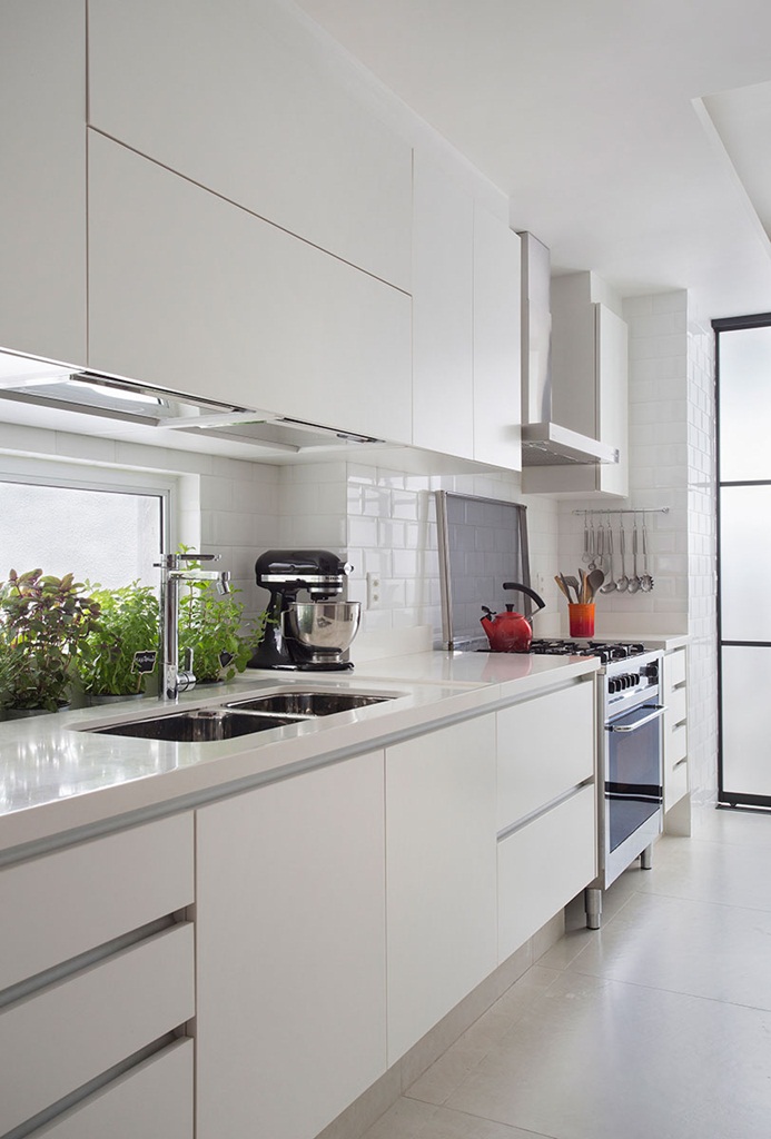 Cozinha pequena com armários brancos e piso cinza, fogão e utensílios de cozinha.