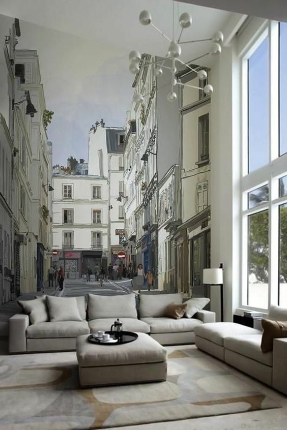 Sala de estar com sofá e mesa de centro com fotomural representando cidade na parede. Trompe l’oeil