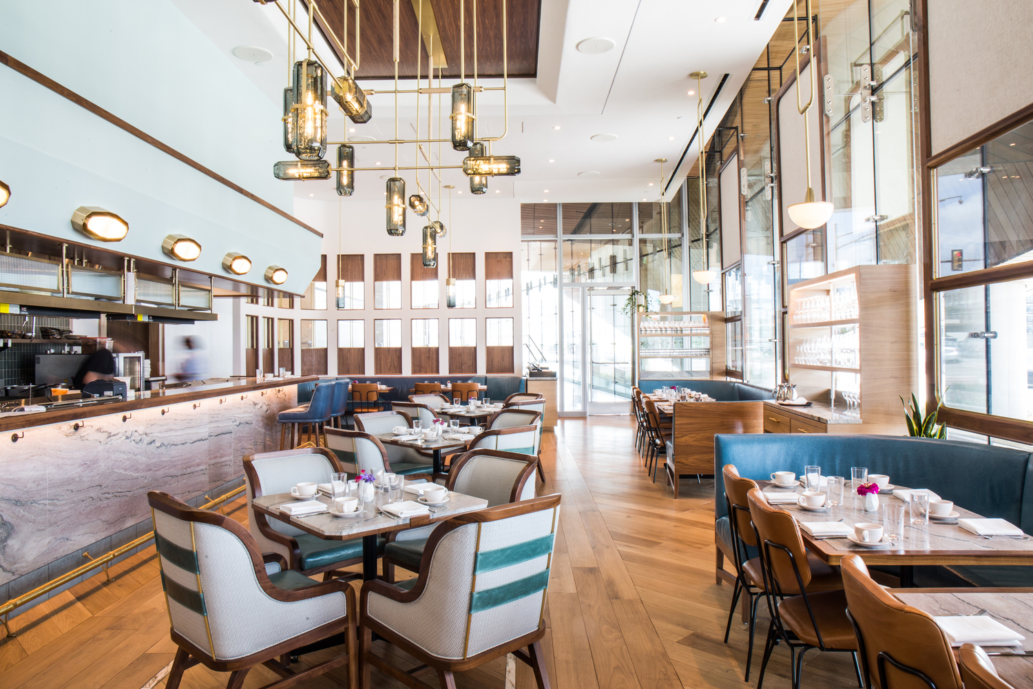 Ambiente de restaurante moderno com piso de madeira, cadeiras e bancos azuis e branco e detalhes em madeira.