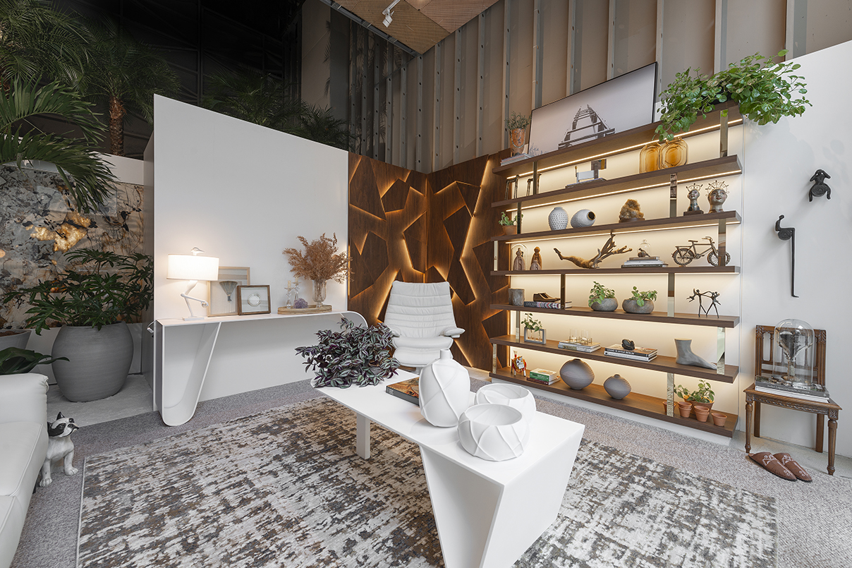Janelas CASACOR - ambiente com mesinha de centro branca, painel branco e amadeirado, prateleiras com objetos decorativos.