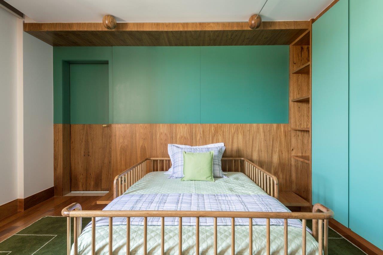 Suite com marcenaria em tons naturais em contraponto com a cor verde, piso de madeira e cama de madeira.