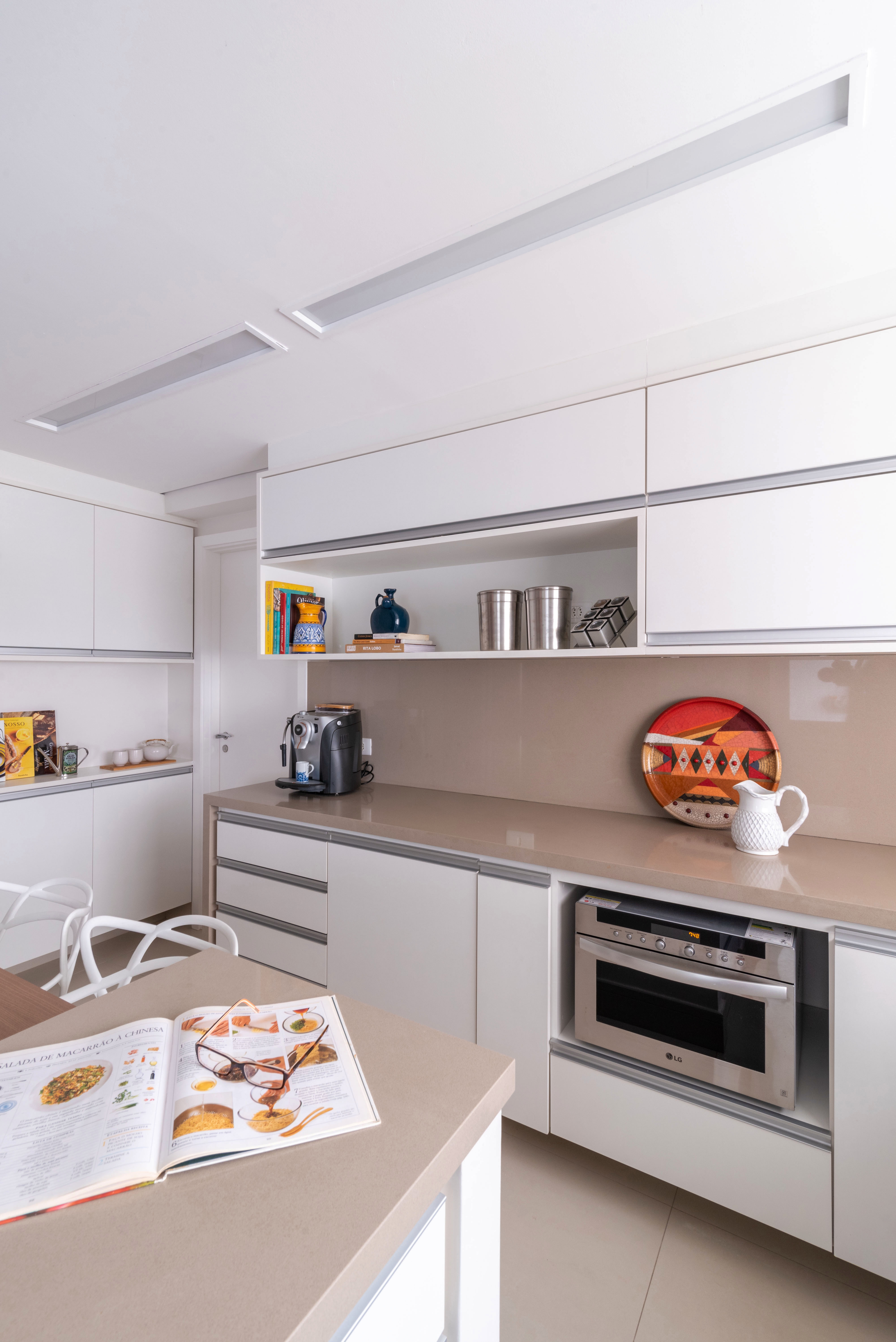 Cozinha com armários em tons neutro, piso neutro e objetos coloridos.