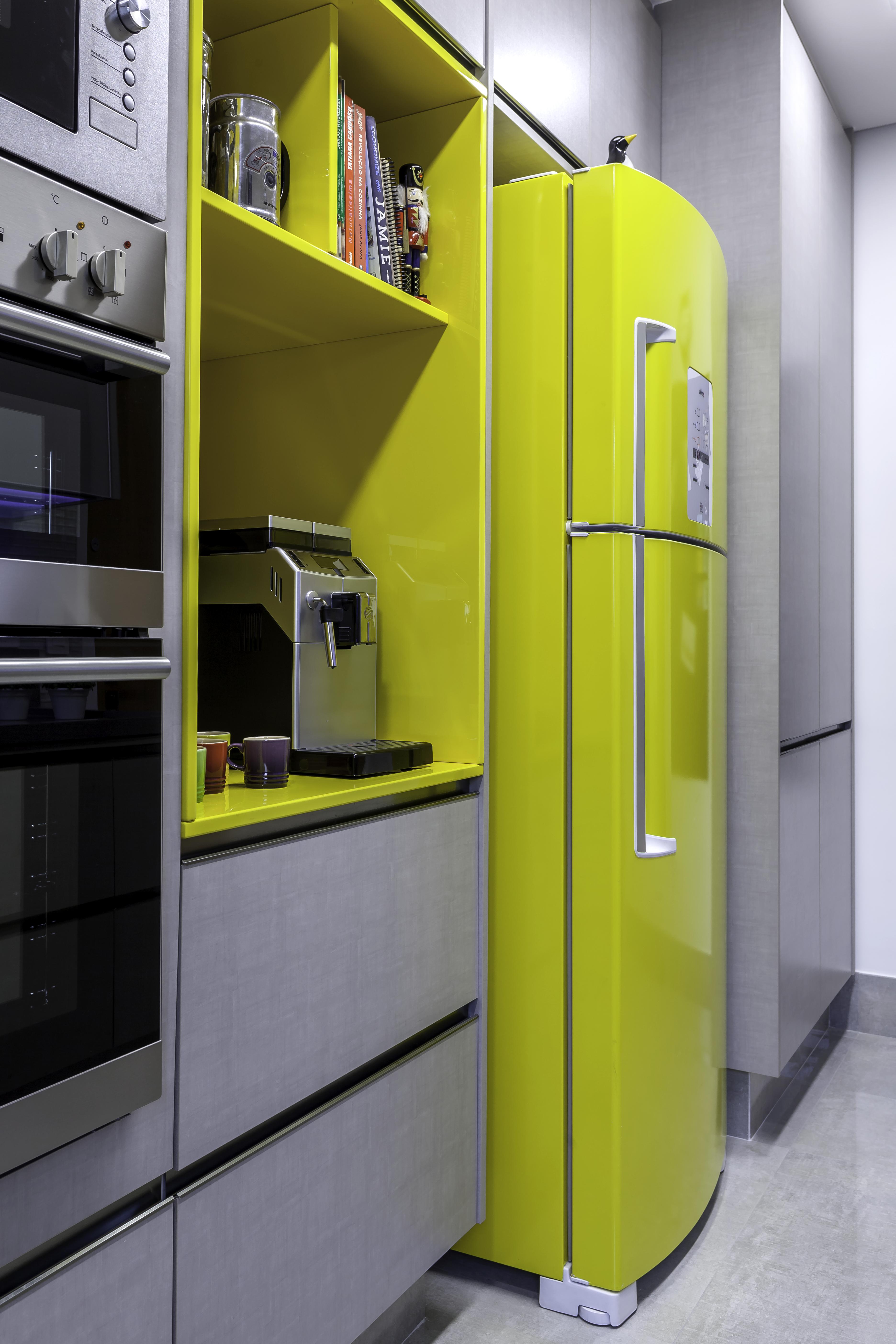 Cozinha com armários e piso cinza, eletrodomésticos de inox e geladeira e nicho do armário amarelos.