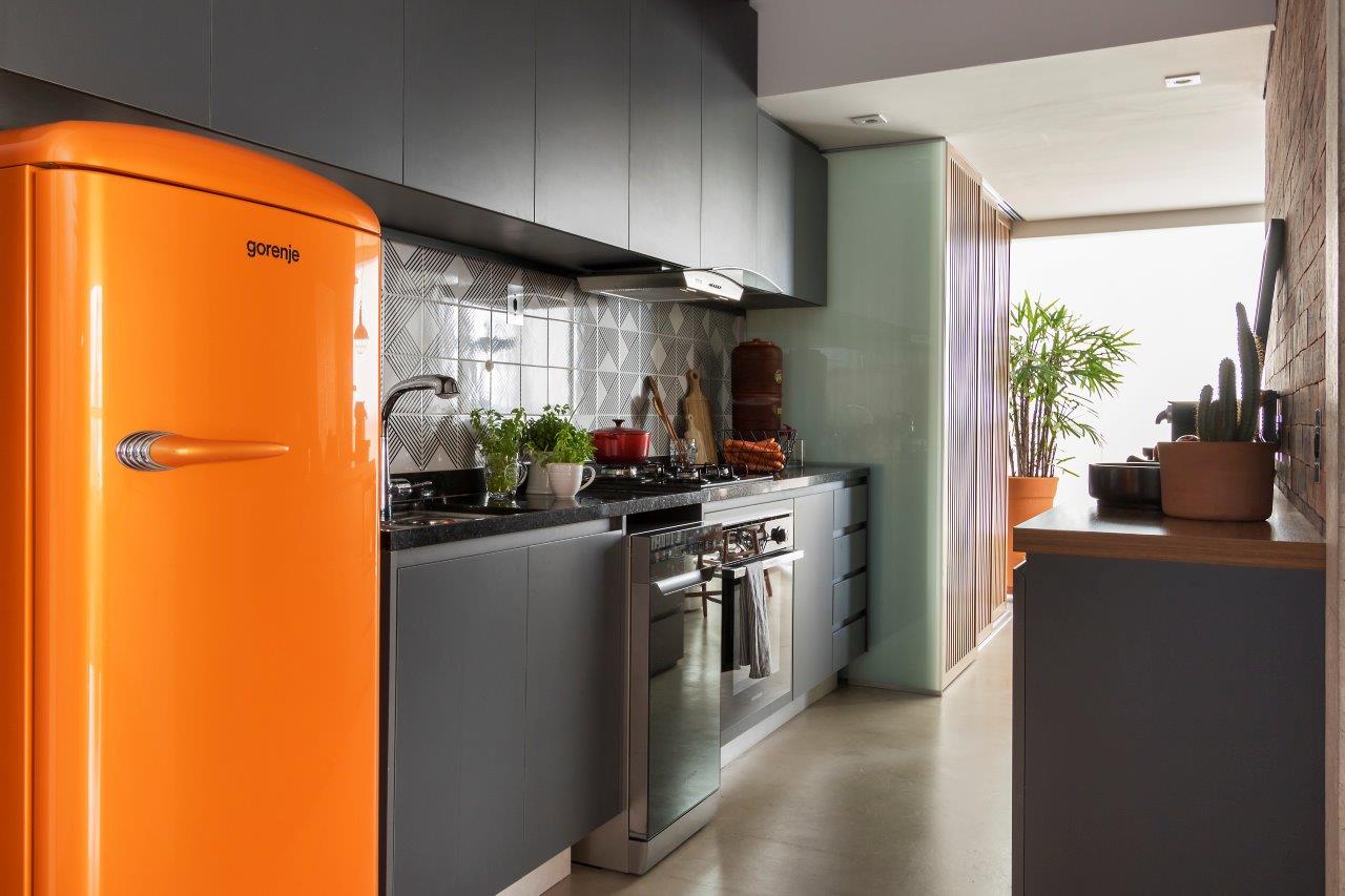Cozinha com armários cinza, bancada amadeirado, pia de granito preto e geladeira laranja.