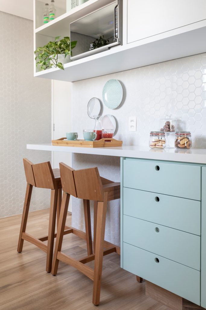 Cozinhas coloridas - Cozinha com armários verdade claro e branco, piso de madeira, bancos de madeira e acessórios verdes.