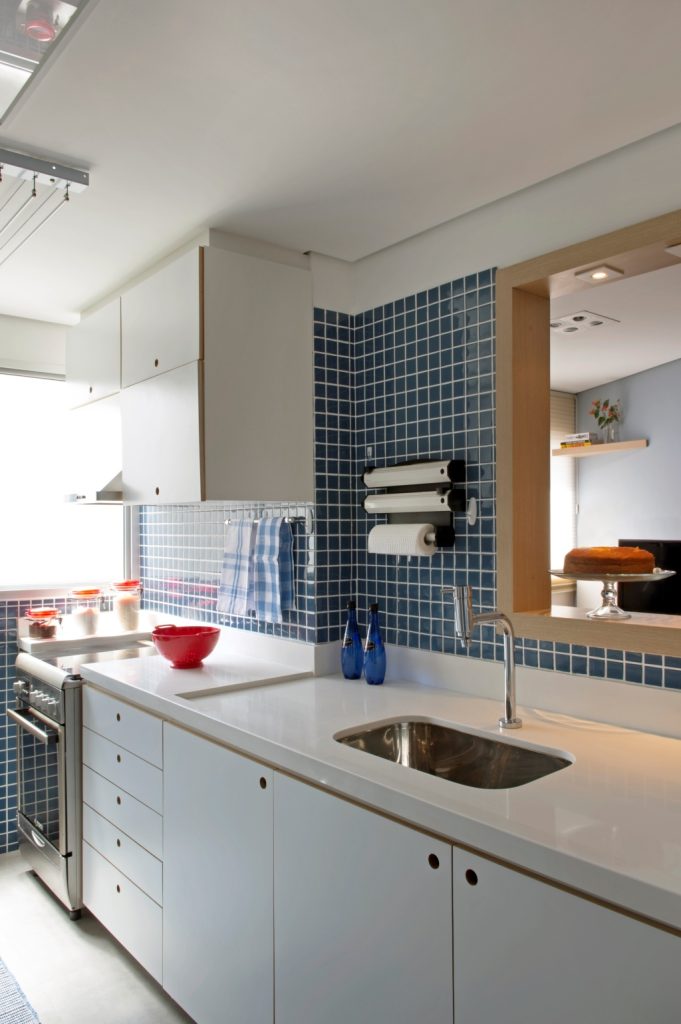 Cozinha com pastilhas em azul mais escuro, suavizadas pelo branco da marcenaria e do piso .