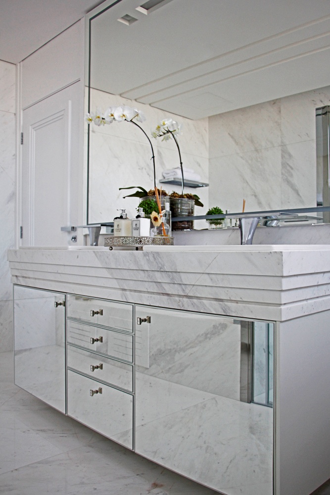 Banheiro mármore branco revestindo paredes, piso, bancada e armário da pia.