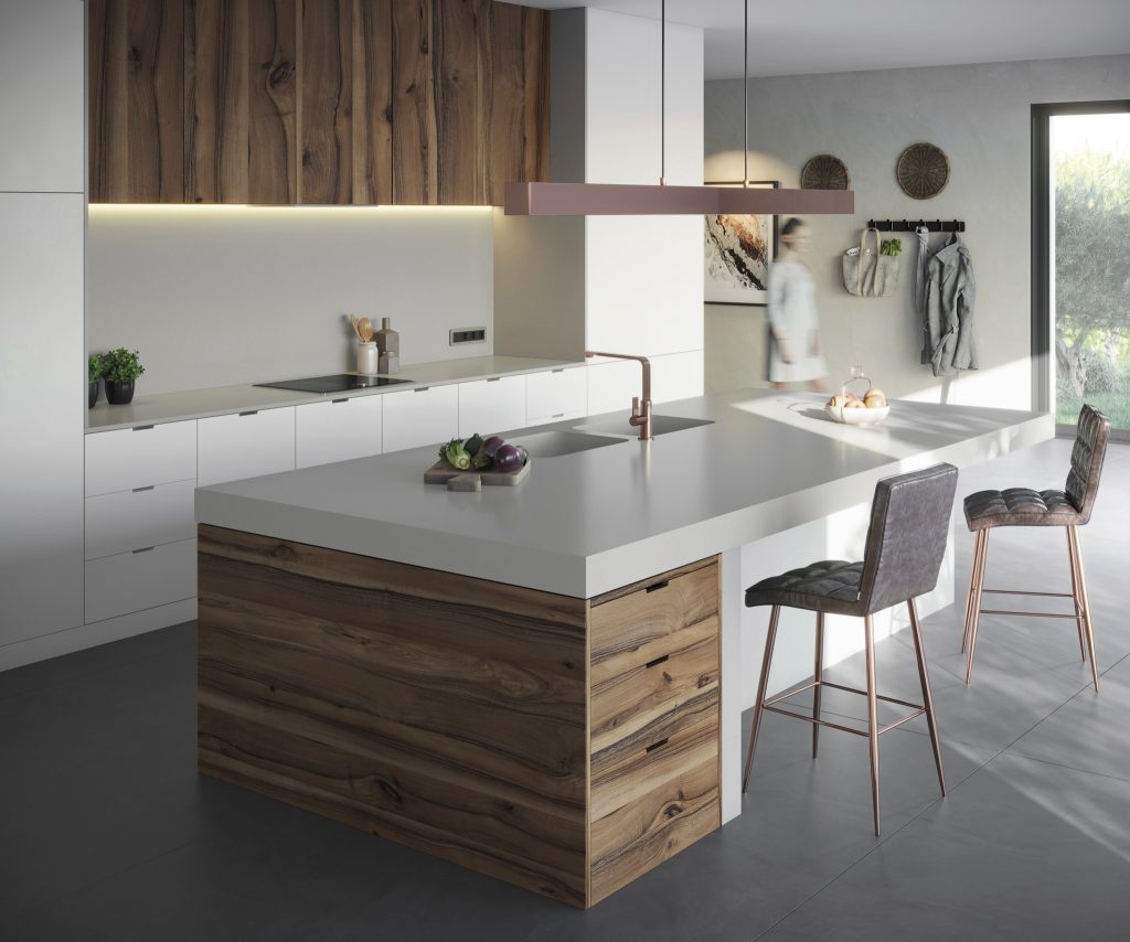 Cozinha com armários amadeirados, superfície da bancada Silestone® Cincel Grey, piso em tom neutro, luminária pendente e cadeiras altas estofadas.