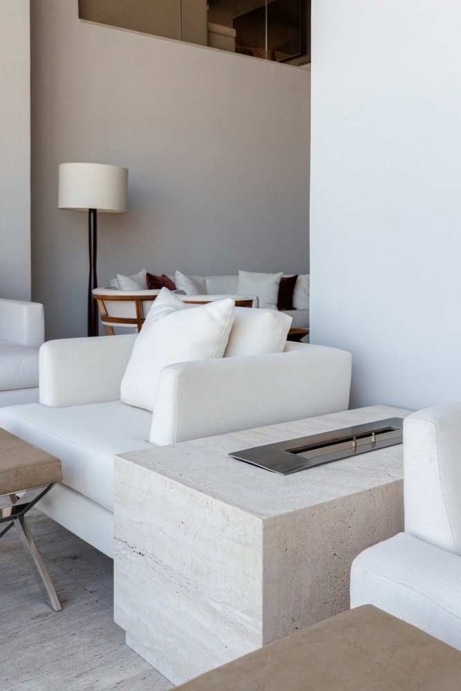 Sala de estar com sofá branco, lareira ecológico, a álcool, revestida de mármore branco.