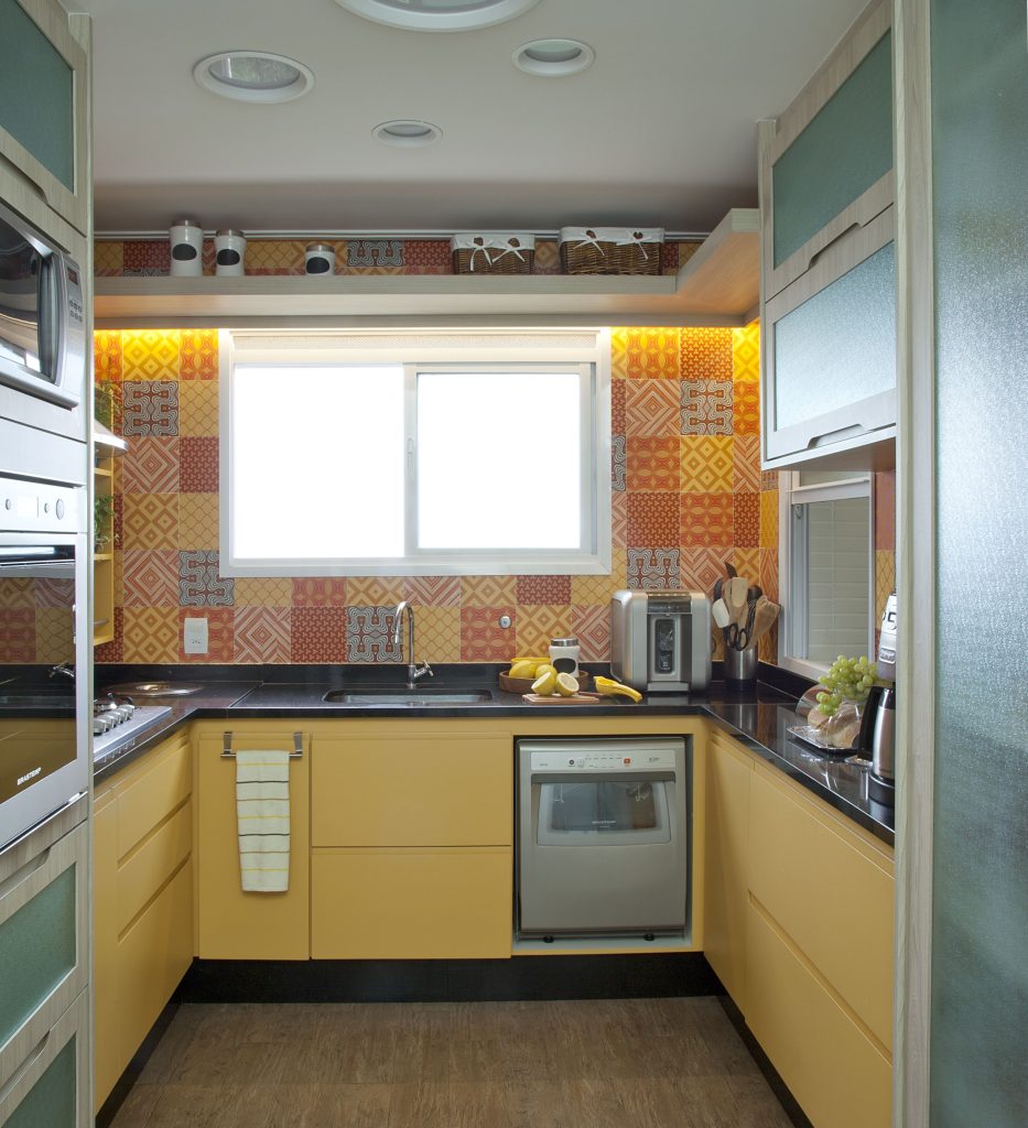 Nesta cozinha, os profissionais propuseram um azulejo colorido, que remete ao visual do ladrilho hidráulico, para evidenciar o amarelo da marcenaria
