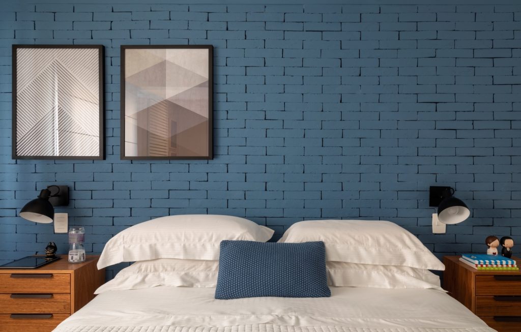 Cultura Geek: quarto de casal com parede de tijolinhos azul, cama sem cabeceira e dois criados mudo marrom