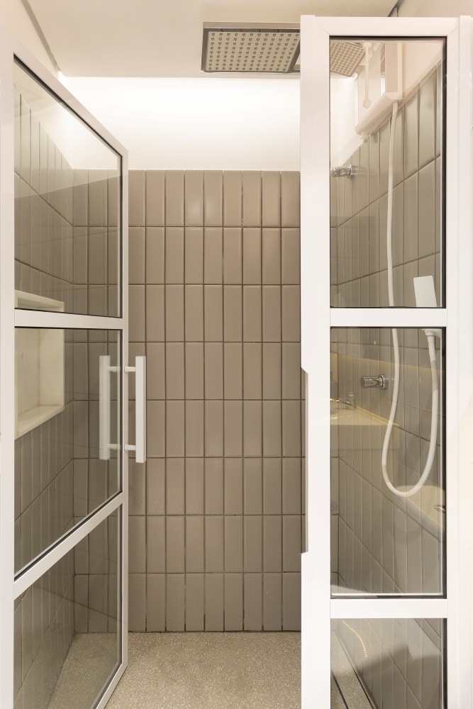 Necessidades do morar e trabalhar: Banheiro com azulejo do metro em tom neutro, piso em tom neutro e box de vidro com moldura branca