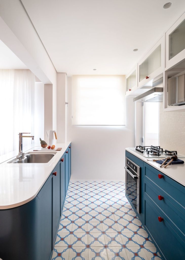 Cozinha com paredes e teto pintados de branco, armário azuis e brancos, piso de ladrilho hidráulico azul e branco