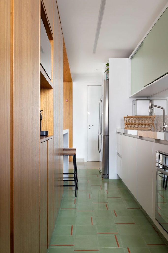 Cozinha estreita com armários verde e branco e piso ladrilho hidráulico verde personalizado.