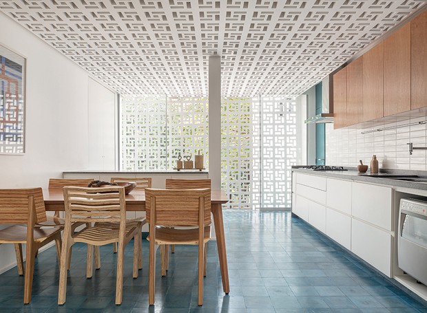 Cozinha com piso ladrilho hidráulico azul valorizando o elemento vazado do teto e uma parede de cobogó branco.. 