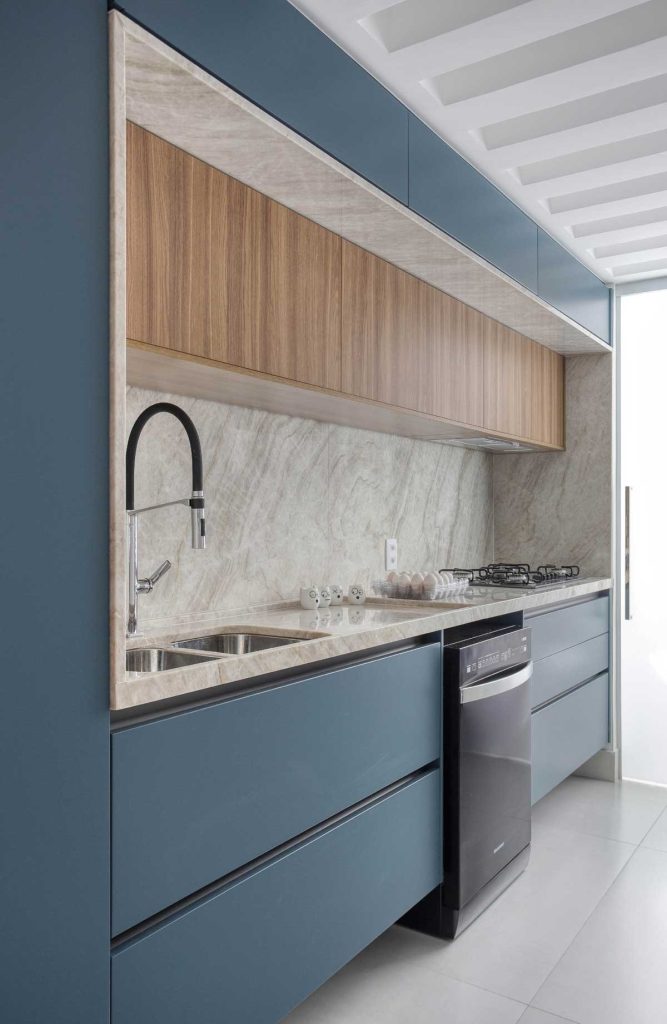 Marcenaria de cozinha azul, com parte interna revestida de granito matira e piso branco