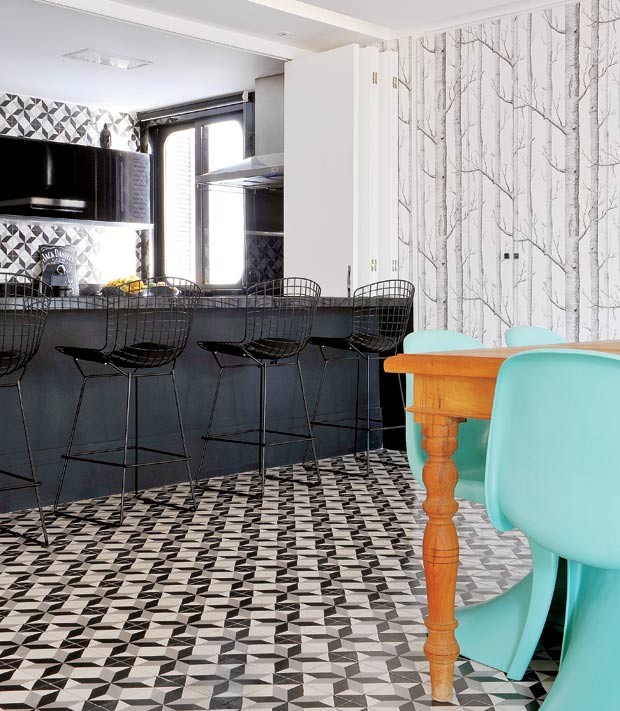 Cozinha integrada a sala de jantar com decoração em preto e branco e destaque em mesa de madeira clara com cadeiras azul tiffany. Piso de ladrilho hidráulico preto e branco