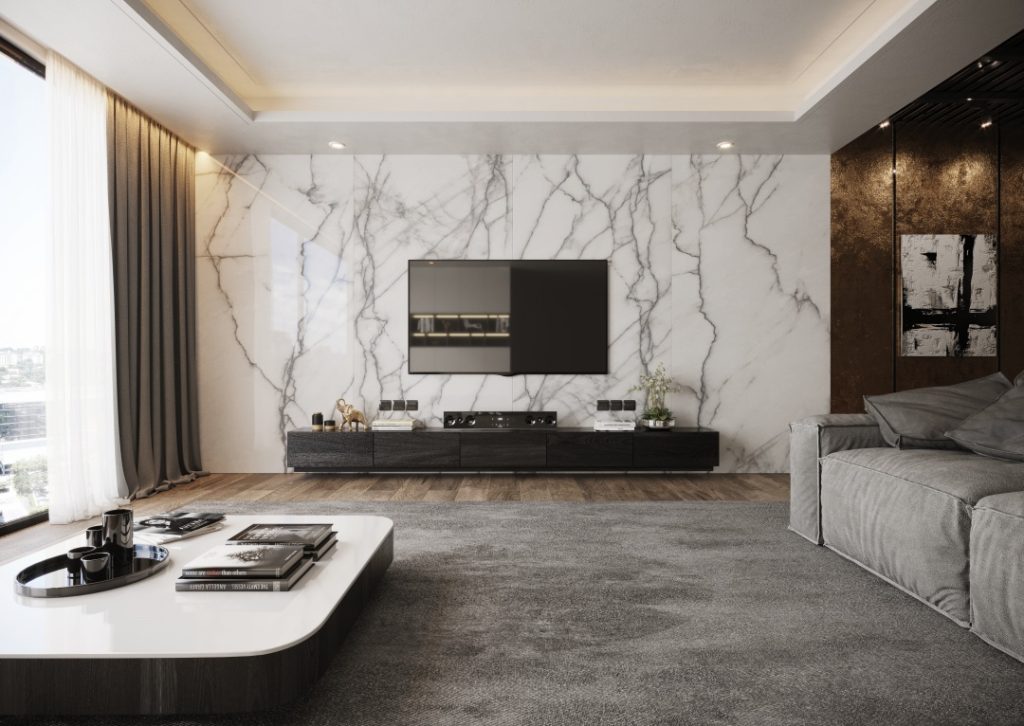 Sala de estar com Porcelanatos SuperFormato aplicado no painel de tv, tapete grande cinza, mesinha de centro e sofá