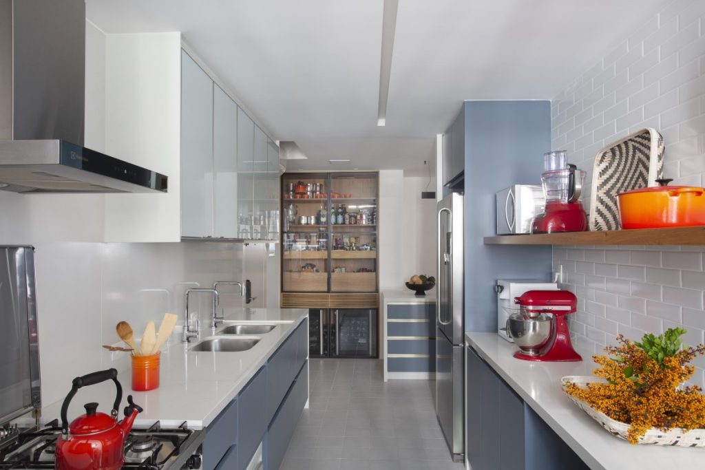 Cozinha com marcenaria cinza, armários brancos, acessórios de cozinha vermelho e subway tiles na parede branco.