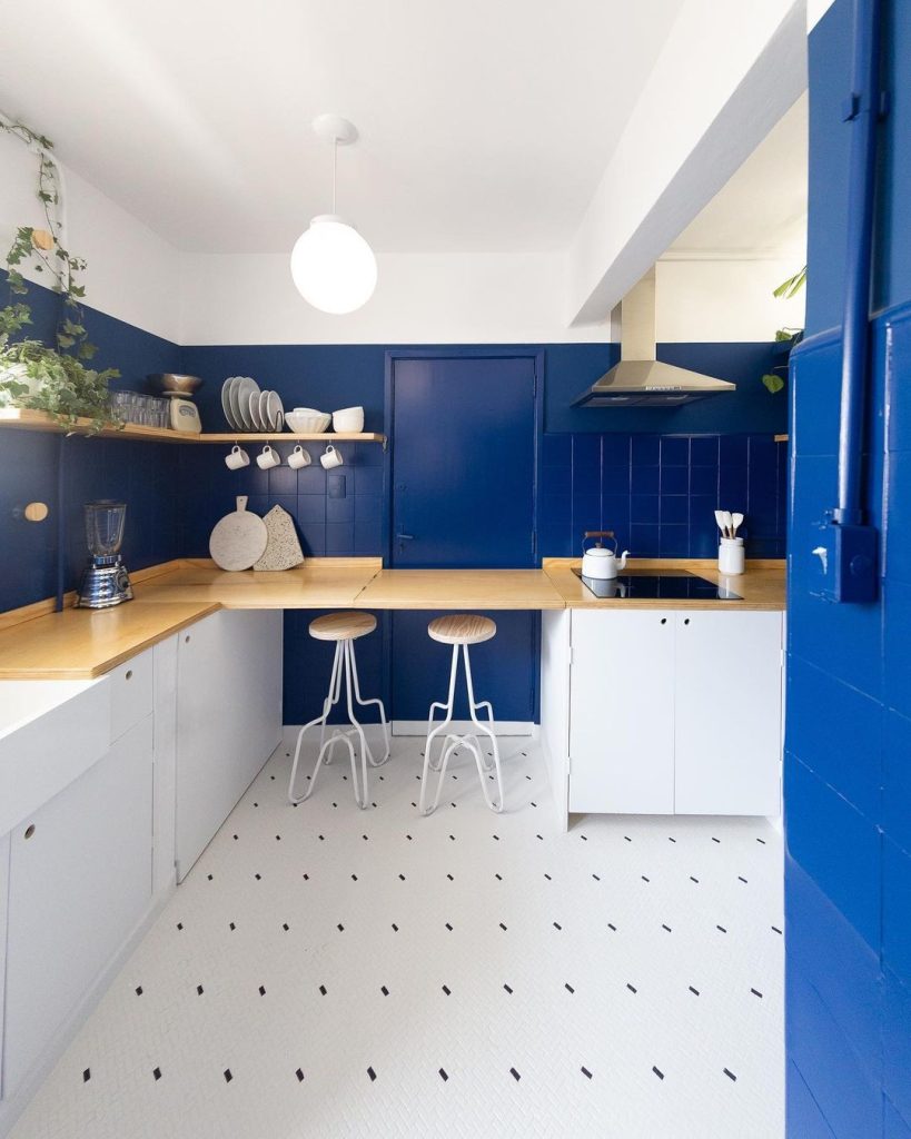 Cozinha com tinta azul para pintar revestimento da parede, piso branco, armários brancos e bancadas de madeira
