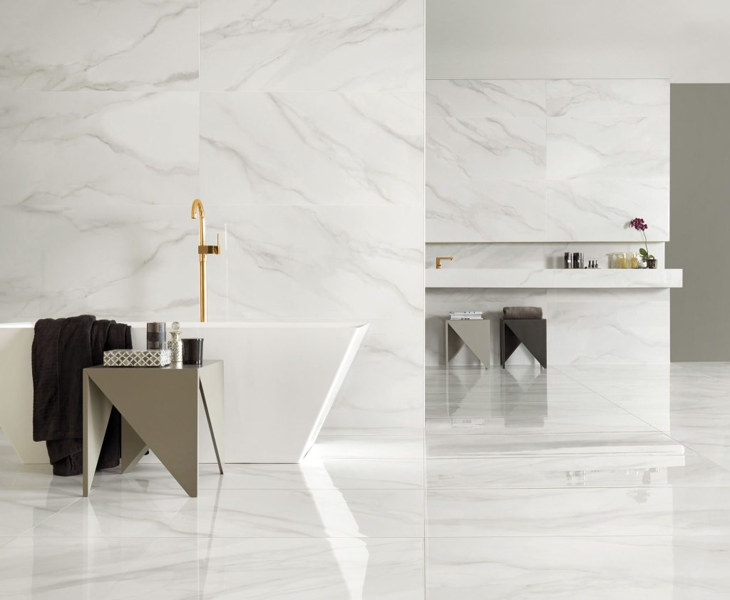 Banheiro com porcelanatos marmorizados revestindo paredes, piso e bancadas