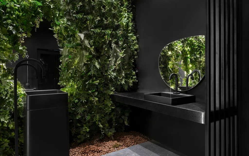 Banheiro com louças e revestimentos da parede preto, jardim vertical na parede principal e piso cinza